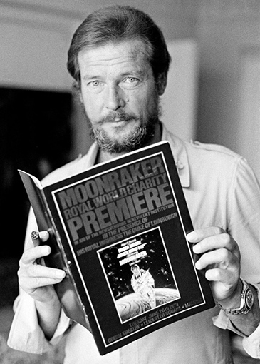 Roger Moore holding the Moonraker premiere brochure