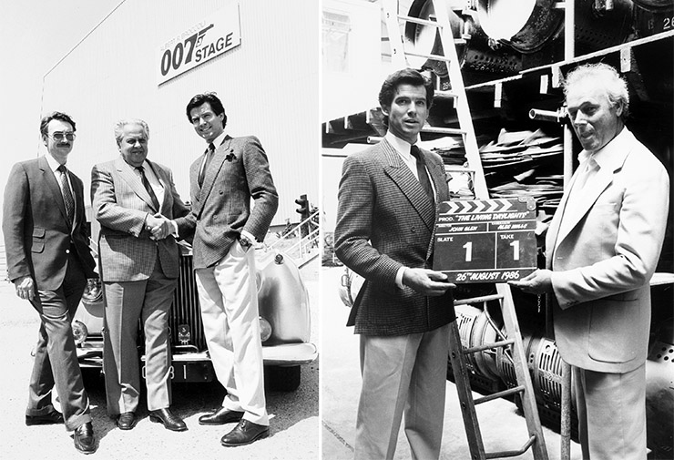Michael G. Wilson, Albert R. Broccoli & Pierce Brosnan at Pinewood Studios 1986 | Brosnan poses with direct John Glen with a mock-up clapperboard bearing the date 25th August 1986 when The Living Daylights was due to start shooting