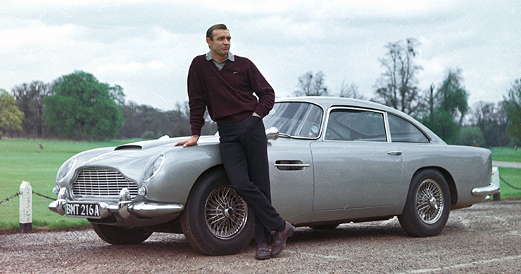 Sean Connery poses with the Aston Martin DB5 on location at Stoke Poges Golf Club