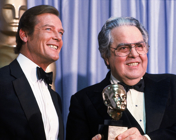 Roger Moore presents the Irving G. Thalberg Memorial Award to Albert R. Broccoli at the 54th Academy Awards Ceremony, held at the Dorothy Chandler Pavilion in Los Angeles on Monday March 29, 1982. 